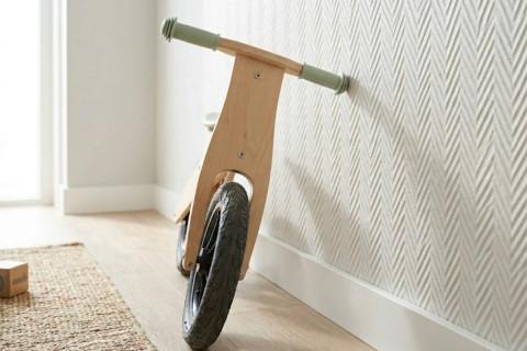 Kinderfietsje staat tegen de muur behangen met glasvezelbehang.